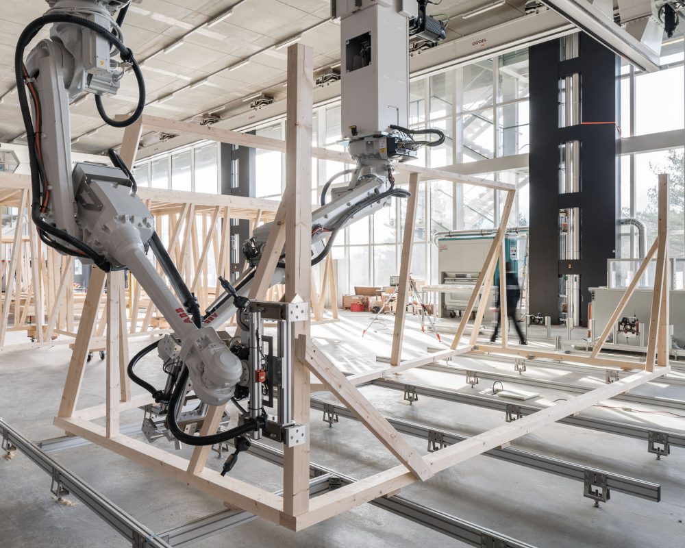 Robotic arms assembling a timber-frame modular structure in a fabrication lab